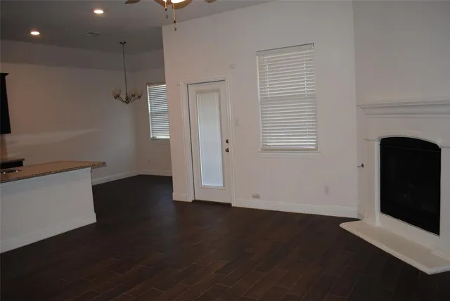 a view of an empty room with wooden floor and a fireplace
