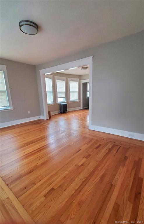 a view of an empty room with window and wooden floor