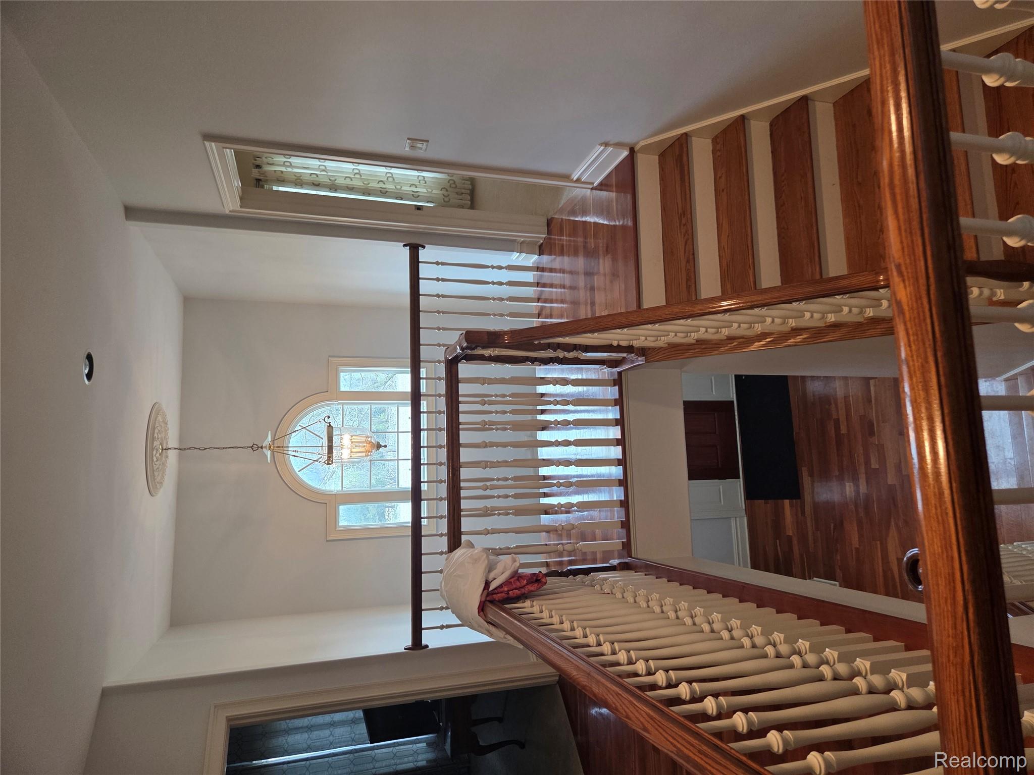 900 South Maxfield Road Brighton, MI 48114 - Photo 13 of 30 Staircase featuring wood finished floors and a chandelier