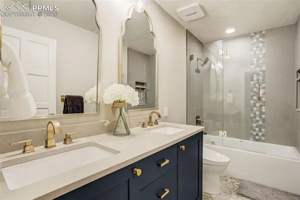 a bathroom with a double vanity sink toilet mirror and bathtub