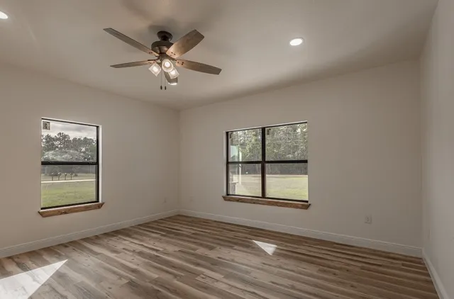 a view of empty room with window and ceiling fan
