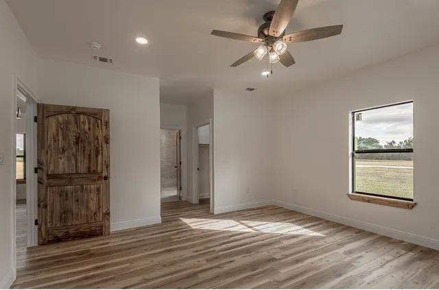 a view of empty room with wooden floor and fan