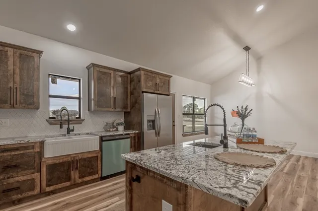 a large kitchen with kitchen island a stove a sink dishwasher and wooden cabinets with wooden floor