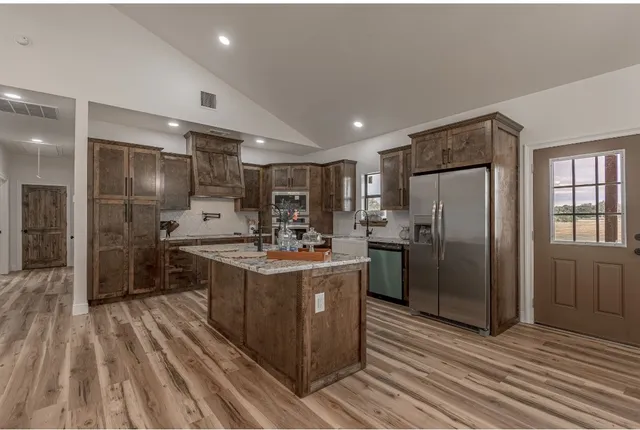 a kitchen with stainless steel appliances kitchen island granite countertop a refrigerator and cabinets