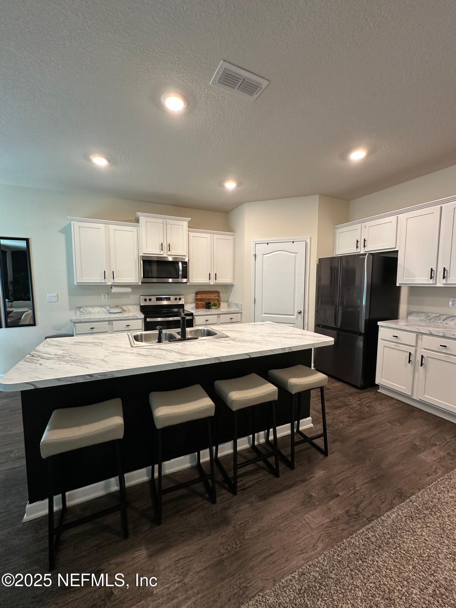 2062 Garrison Way Green Cove Springs Green Cove Springs, FL 32043 - Photo 11 of 56 a kitchen with stainless steel appliances granite countertop a table chairs sink refrigerator and cabinets