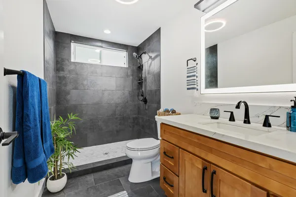 a bathroom with a granite countertop sink a toilet and shower