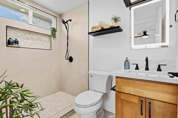a bathroom with a granite countertop sink toilet and mirror
