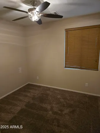 an empty room with a ceiling fan and window