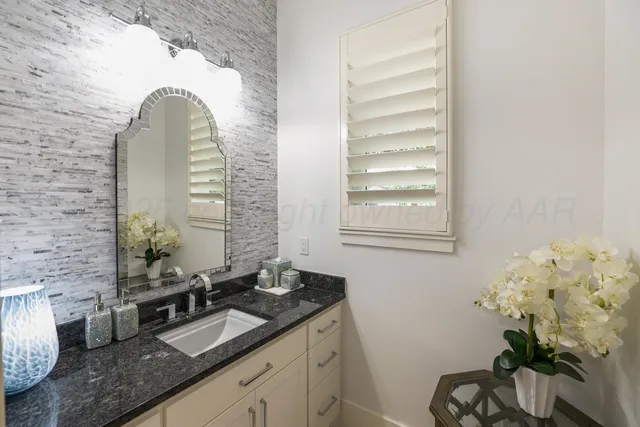 a bathroom with a granite countertop sink a potted plant and a mirror