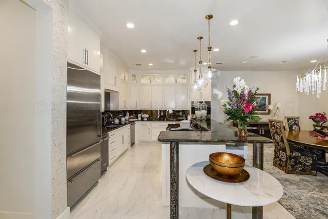 a kitchen with stainless steel appliances a dining table chairs and a refrigerator