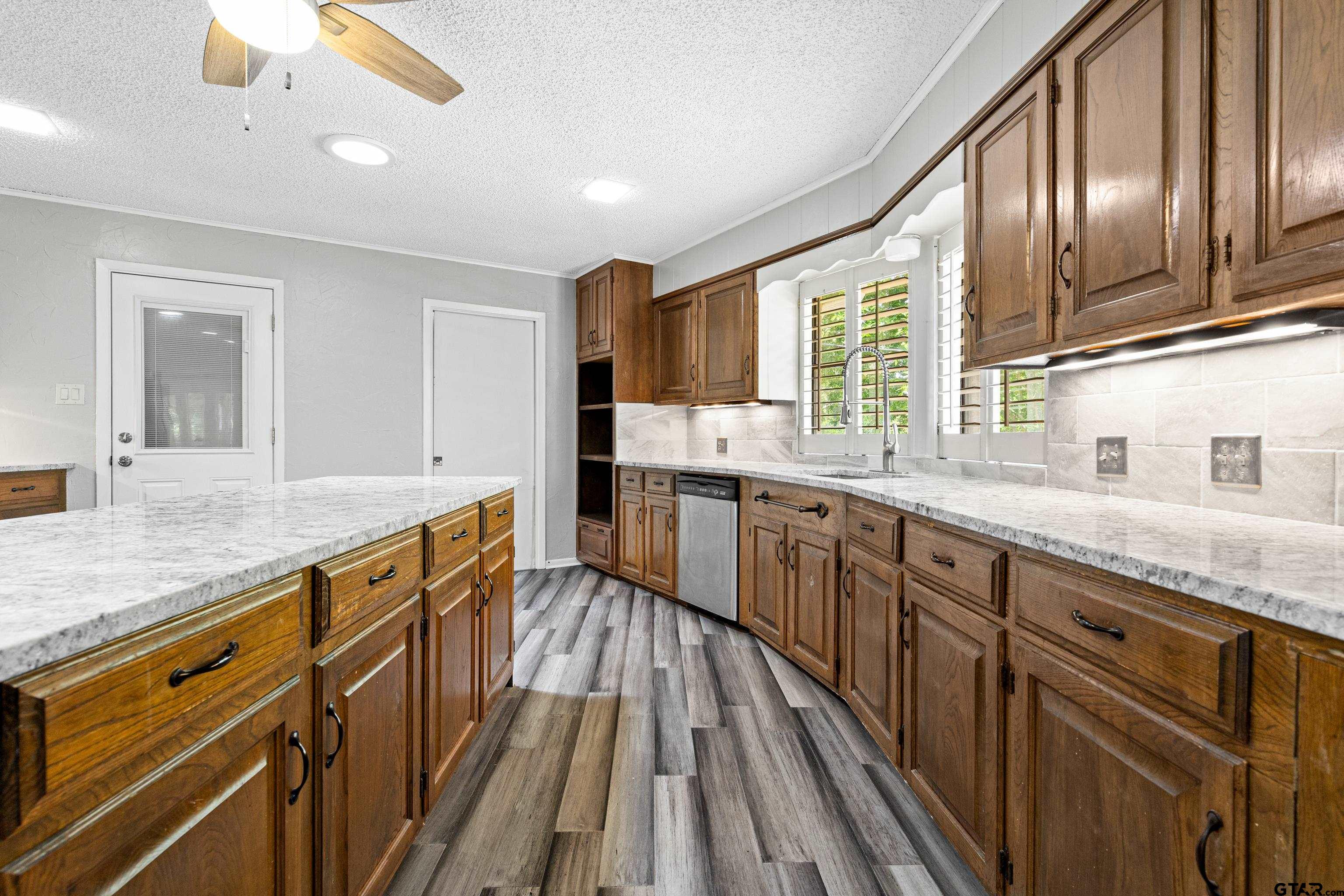 1821 Azalea Street Gilmer, TX 75644 - Photo 9 of 34 a large kitchen with kitchen island granite countertop wooden floor stainless steel appliances and cabinets