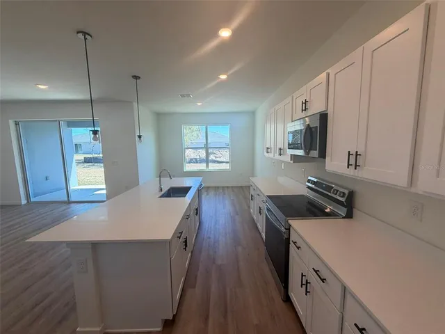 a kitchen with granite countertop a sink a counter space appliances and cabinets