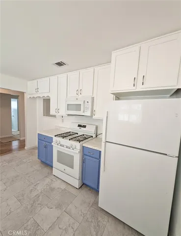 a kitchen with a refrigerator a stove top oven and white cabinets