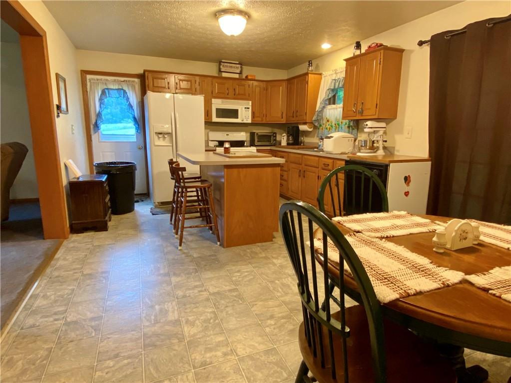 1564 Hells Kitchen Road Polk, PA 16342 - Photo 9 of 25 a kitchen with stainless steel appliances kitchen island granite countertop a table chairs and a refrigerator