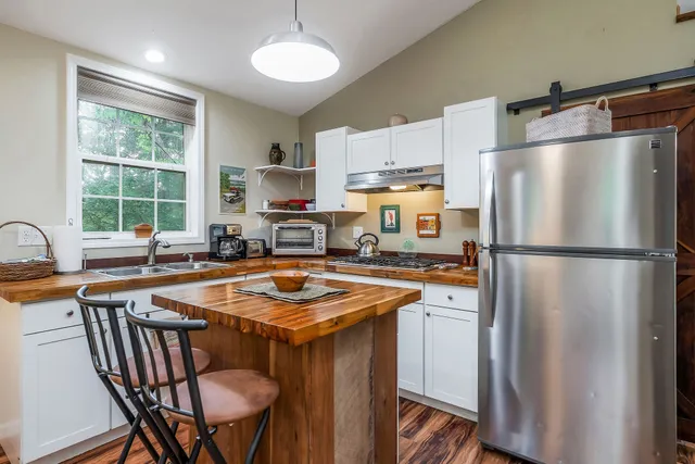 a kitchen with stainless steel appliances granite countertop a refrigerator a sink a stove a dining table and chairs