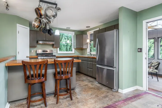 a kitchen with stainless steel appliances granite countertop a dining table chairs sink and refrigerator