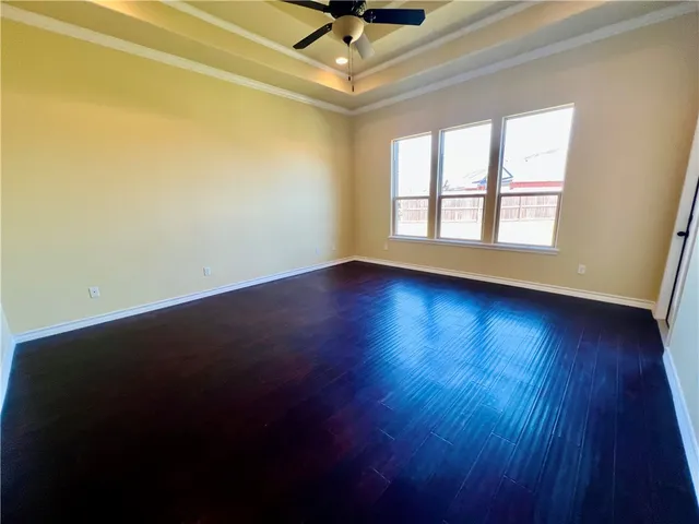 an empty room with wooden floor fan and windows