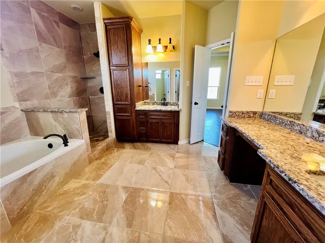 a spacious bathroom with a granite countertop tub sink and mirror