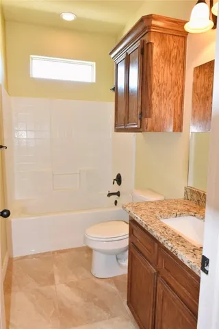 a bathroom with a granite countertop sink a toilet and bathtub
