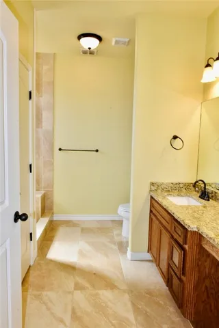 a bathroom with a granite countertop sink mirror vanity and toilet