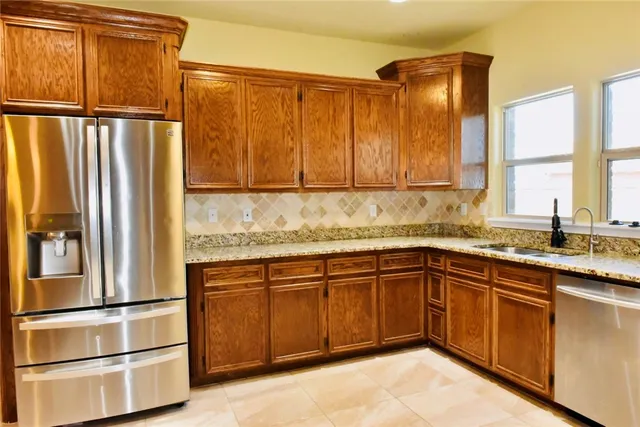 a kitchen with stainless steel appliances granite countertop a refrigerator and a sink