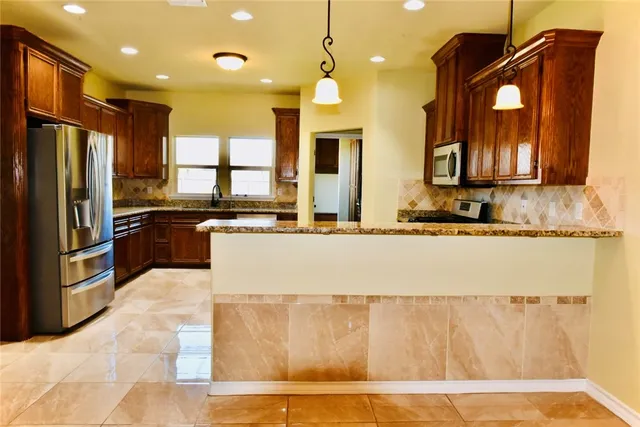 a kitchen with stainless steel appliances granite countertop a sink a stove and a refrigerator