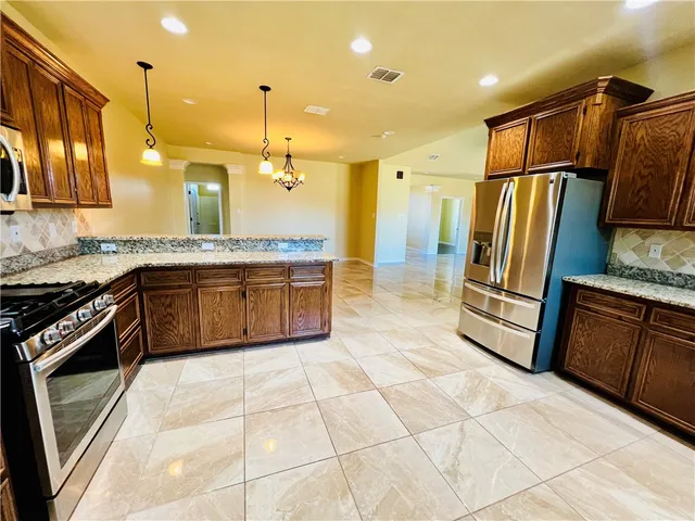 a kitchen with stainless steel appliances granite countertop a stove a sink and a refrigerator