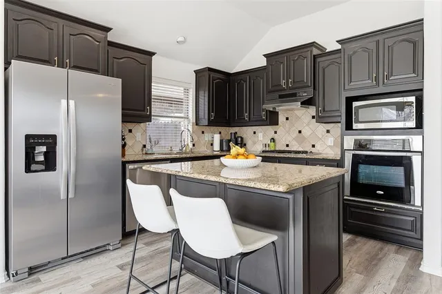 a kitchen with granite countertop a refrigerator stove and microwave
