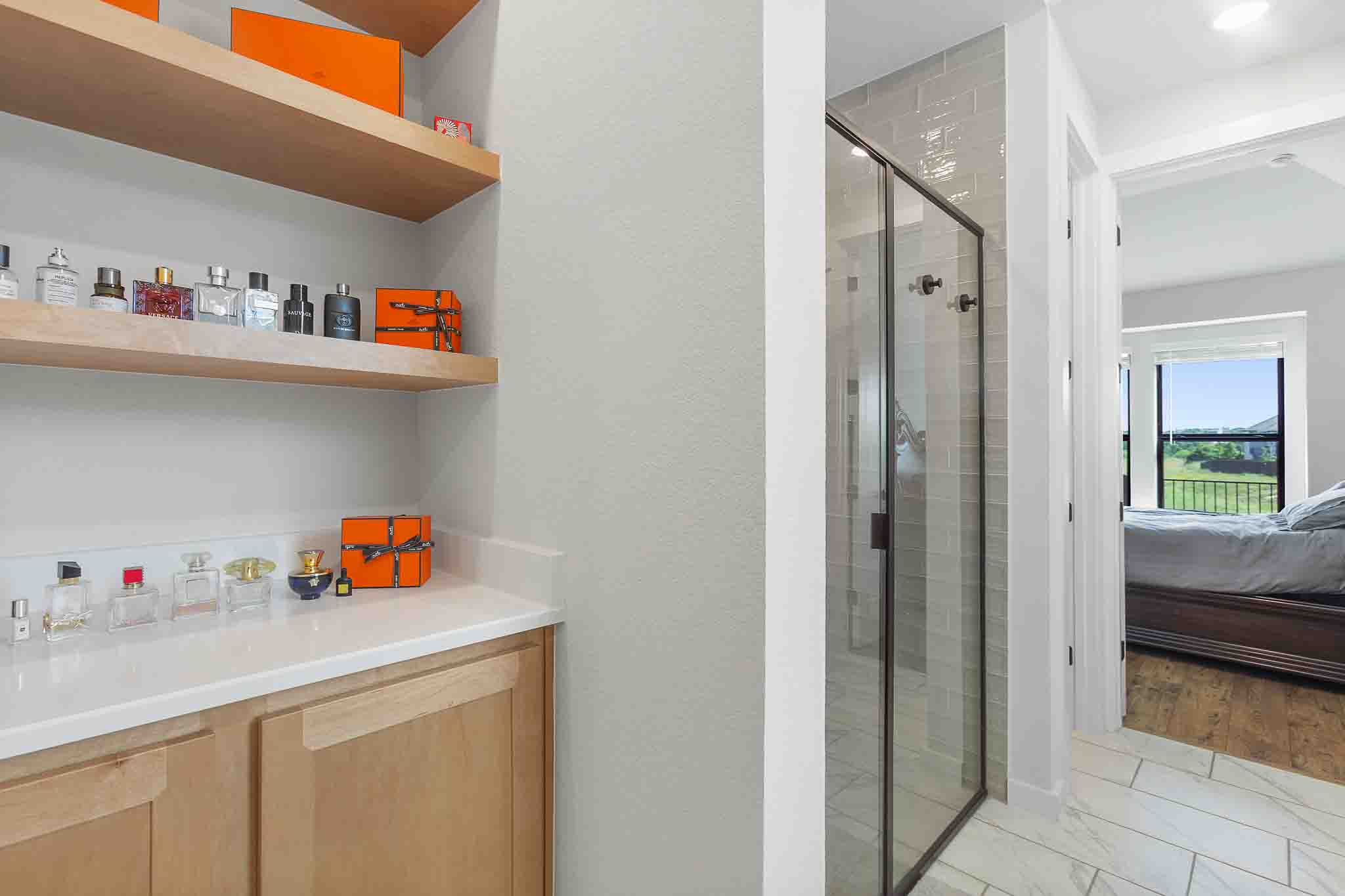 220 Basket Flower Loop Kyle, TX 78640 - Photo 20 of 40 Enjoy the spa-like atmosphere of this modern primary bathroom featuring a sleek glass-enclosed shower and chic shelving.