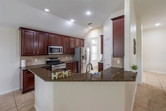 a kitchen with stainless steel appliances granite countertop wooden cabinets a stove a sink and a refrigerator