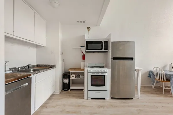 a kitchen with stainless steel appliances granite countertop a stove a refrigerator and a stove top oven