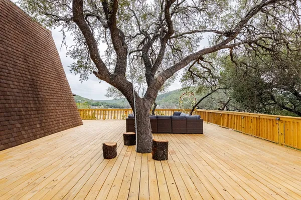 a view of balcony with wooden floor and large trees
