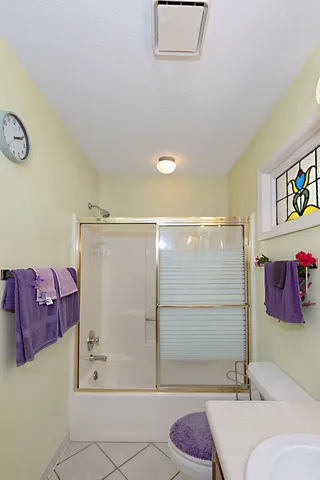 a bathroom with a granite countertop tub shower and mirror