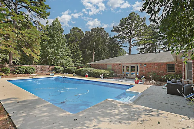 a view of swimming pool with outdoor seating and trees in the background