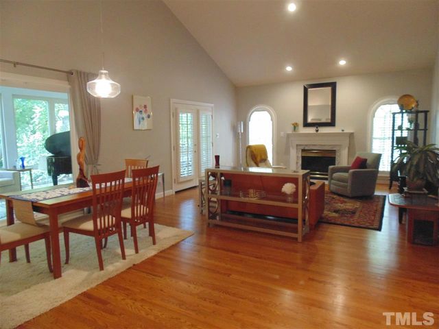a living room with furniture a fireplace and a dining table with wooden floor