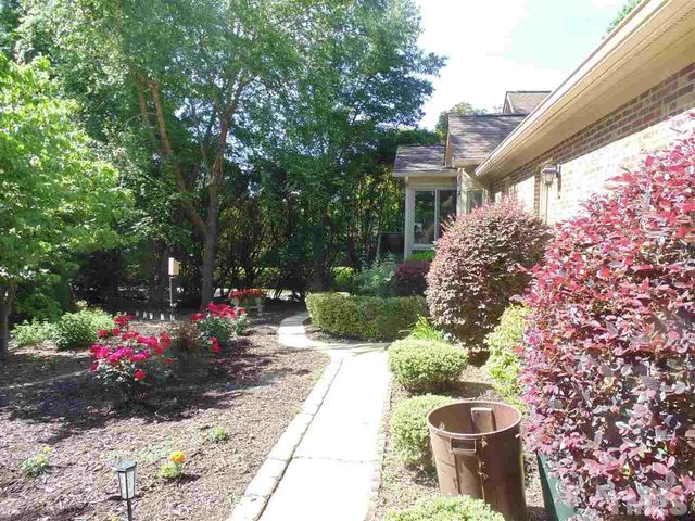 a view of a garden with flowers and large trees