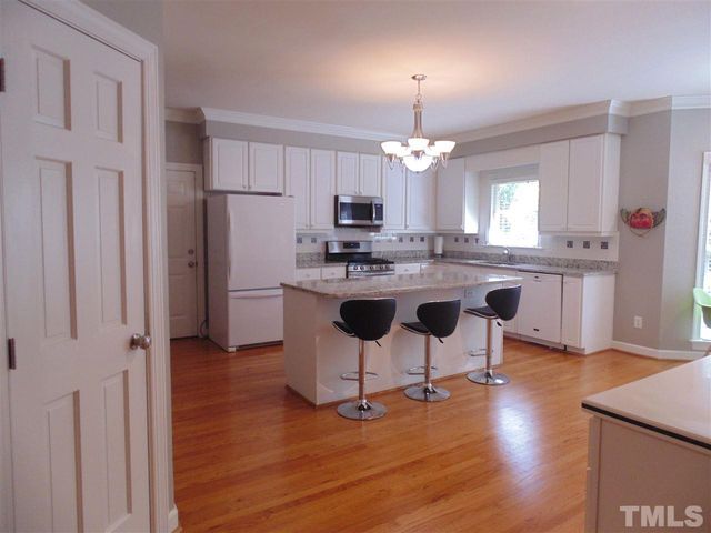 a kitchen with kitchen island granite countertop a sink cabinets and wooden floor