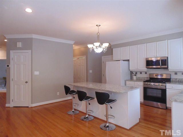 a kitchen with stainless steel appliances granite countertop a refrigerator a stove top oven a sink dishwasher and a dining table with wooden floor