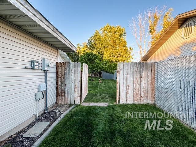 808 O'Leary Way Twin Falls, ID 83301 - Photo 35 of 37 Expansive backyard featuring a green lawn, mature trees, and a wooden privacy fence with a gate