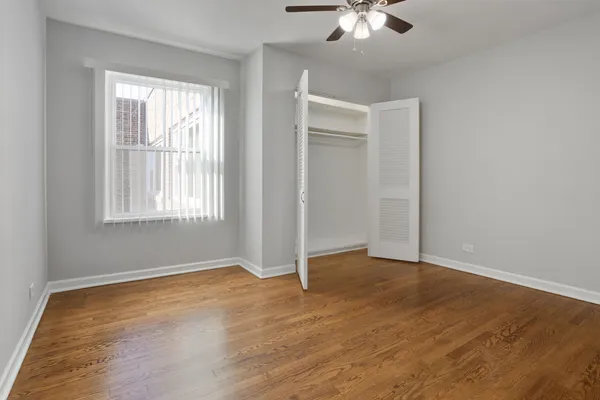 an empty room with wooden floor chandelier fan and windows