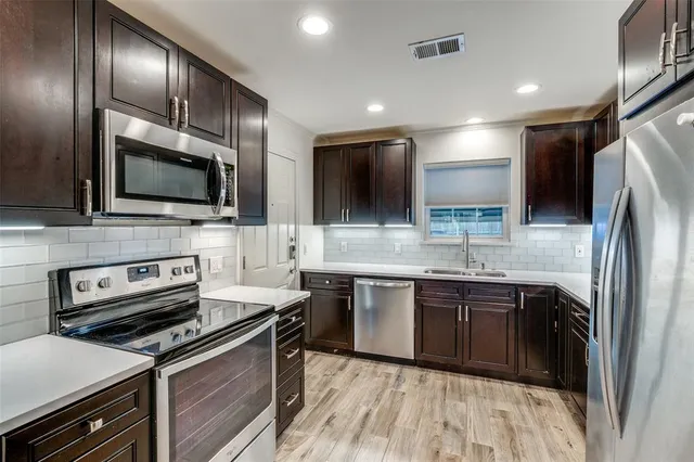 a kitchen with stainless steel appliances granite countertop a refrigerator a stove and a sink