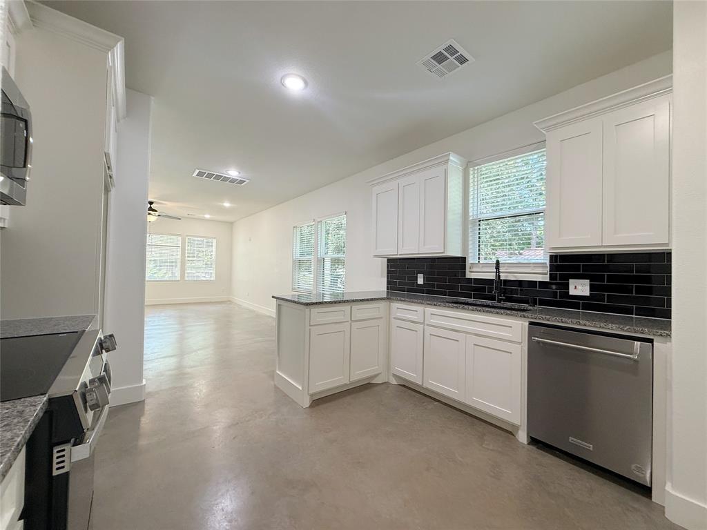 1905 South Lamar Denison, TX 75021 - Photo 11 of 27 Kitchen with finished concrete flooring, stainless steel appliances, a peninsula, tasteful backsplash, and white cabinets