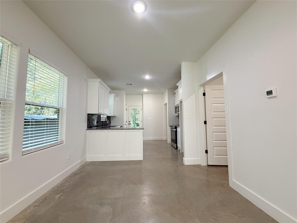 1905 South Lamar Denison, TX 75021 - Photo 7 of 27 Kitchen with finished concrete flooring, recessed lighting, white cabinetry, a peninsula, and dark countertops