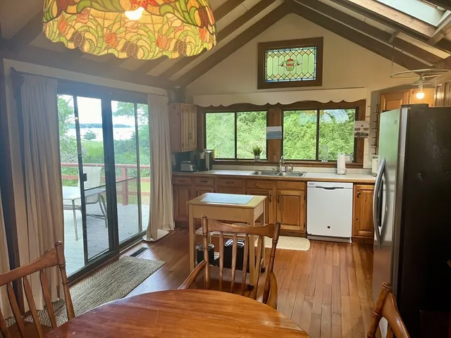 a kitchen with stainless steel appliances granite countertop a stove a refrigerator a microwave oven with a dining table and chairs with wooden floor