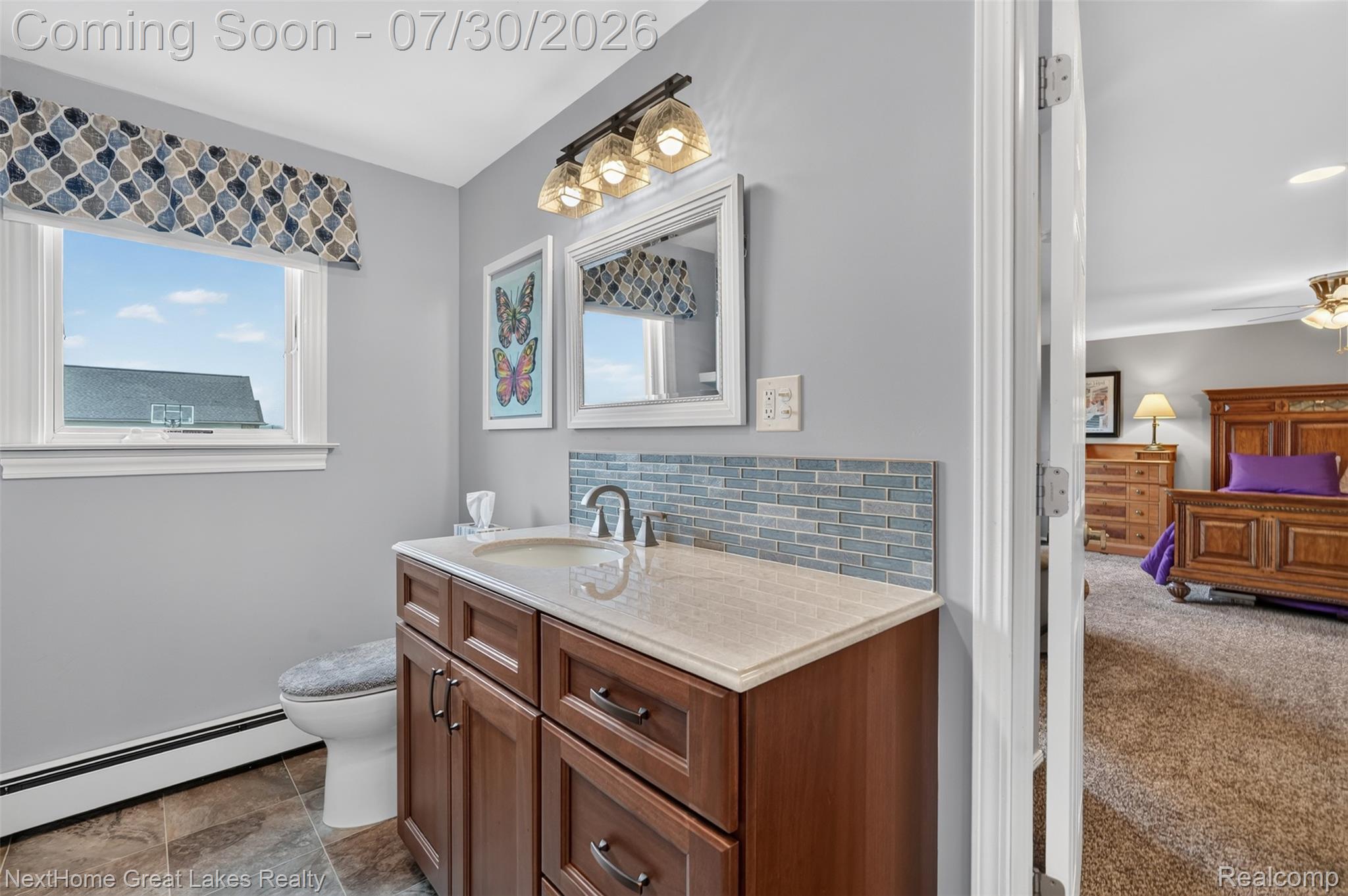 6249 North New Lothrop Road New Lothrop, MI 48460 - Photo 23 of 50 Bathroom featuring a wood-finish vanity with a light-colored countertop, an undermount sink with a chrome faucet, and a blue tile backsplash