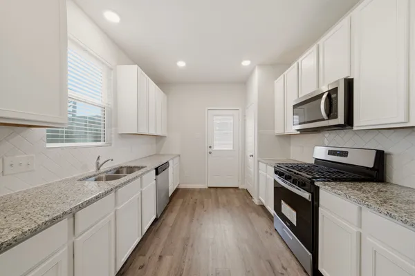 a kitchen with granite countertop wooden cabinets stove top oven and sink