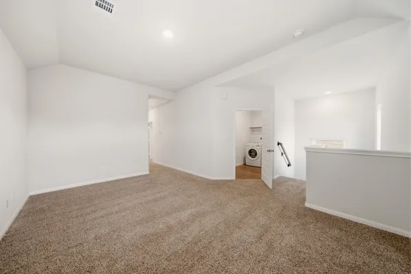 a view of an empty room with wooden floor and windows