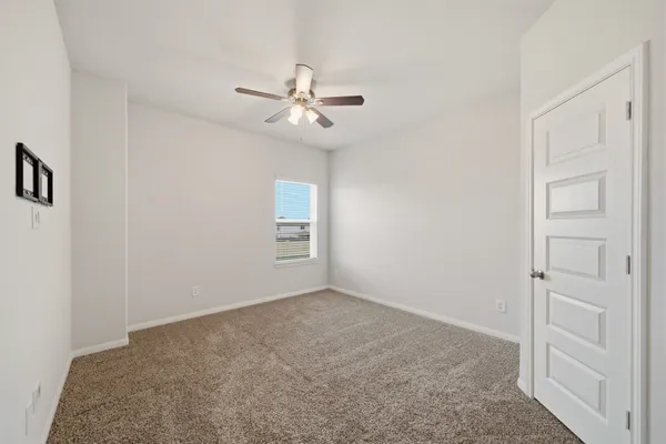 an empty room with windows and fan