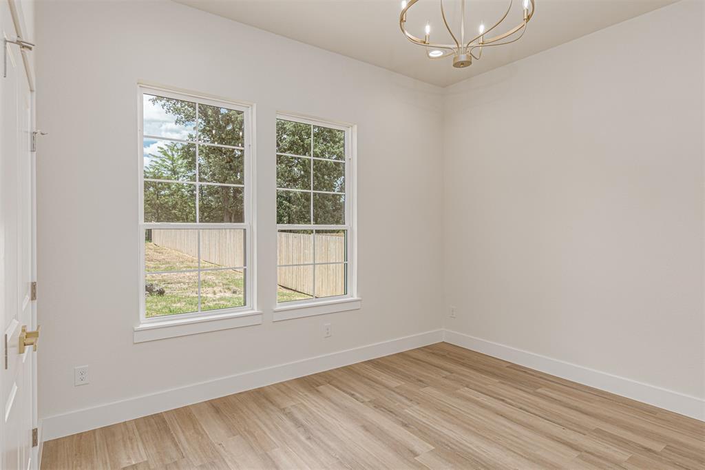 360 Dalton Road Canton, TX 75103 - Photo 21 of 33 Room featuring two double-hung windows, wood-finish flooring, a contemporary chandelier, white baseboards, and a paneled interior door with brass hardware