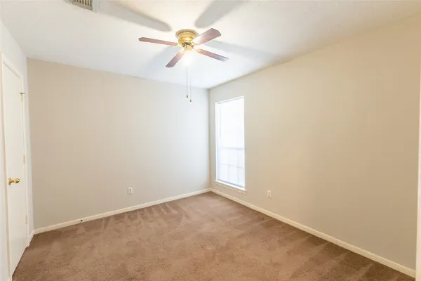 an empty room with a window and a fan